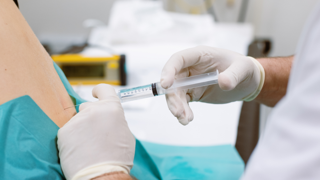 Médico aplicando infiltração na coluna com seringa em procedimento minimamente invasivo